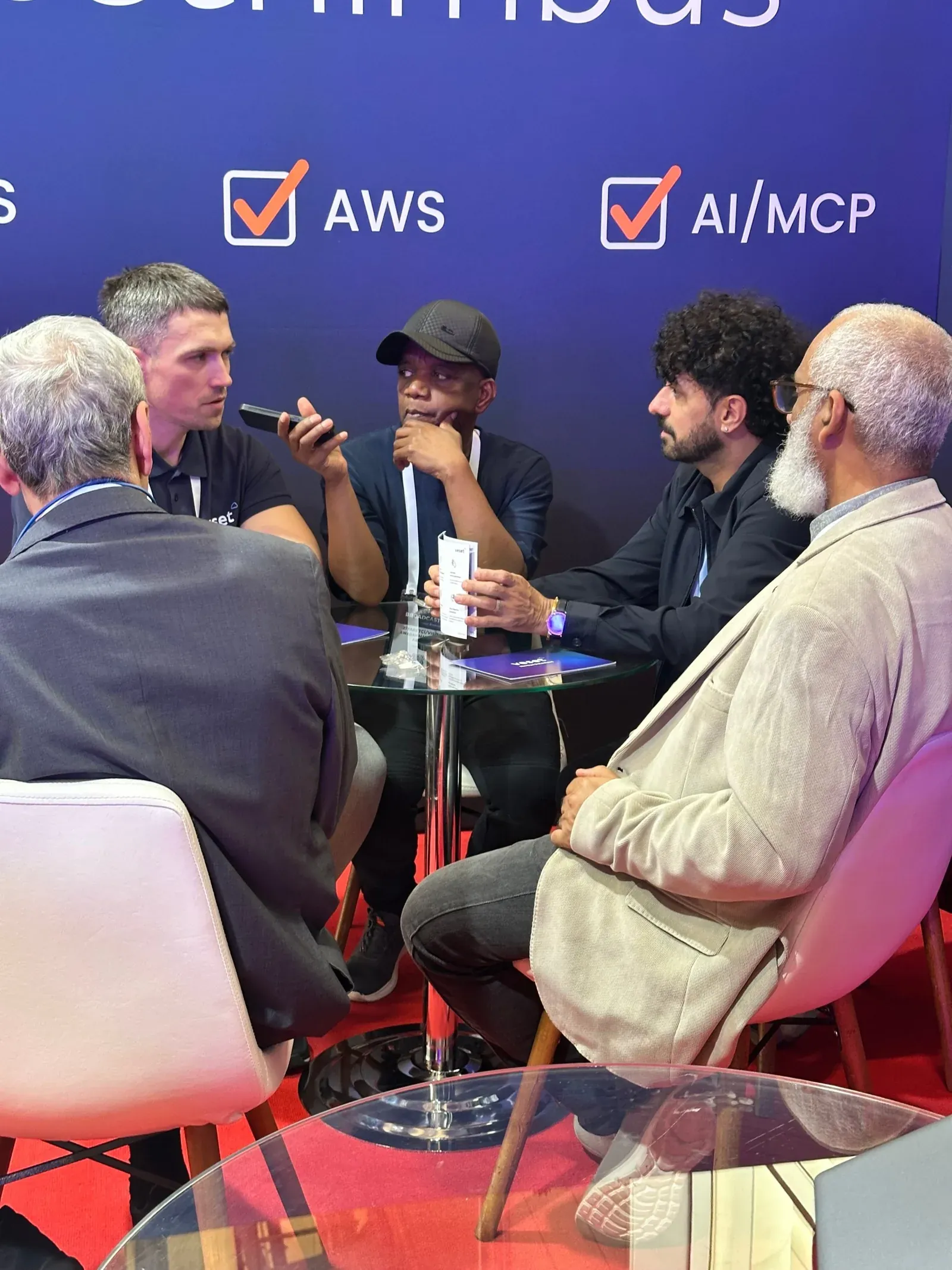 Martins Magone talking with visitors at a table on the Veset stand at BroadcastEx 2026